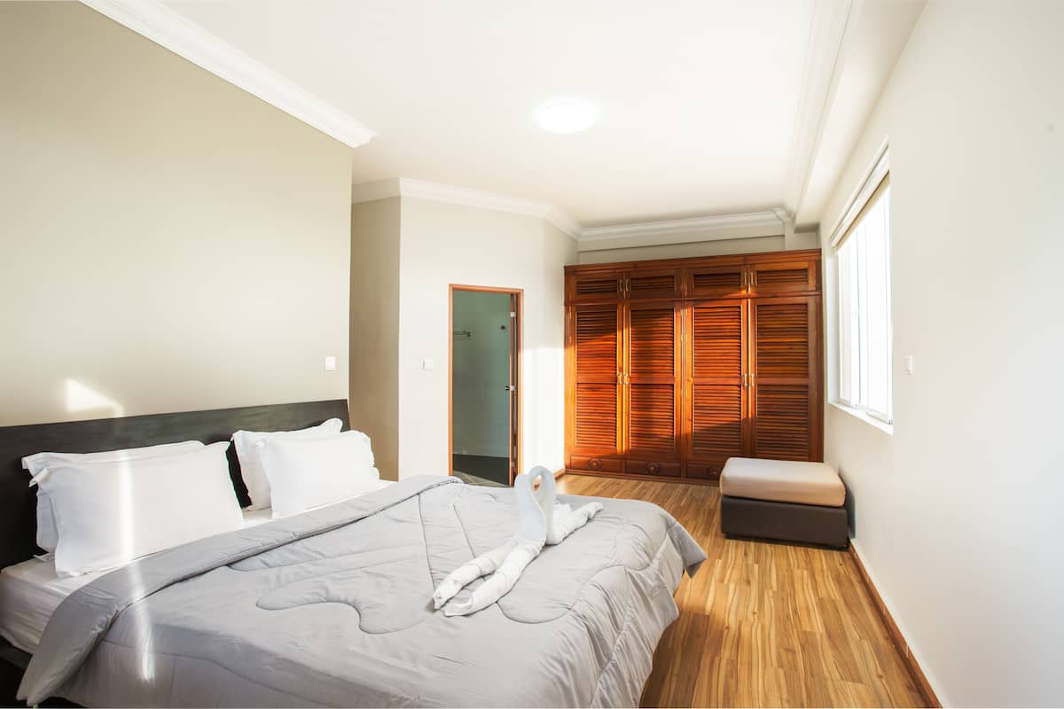 A hotel room with a bed, a bench, a wardrobe, and a door.