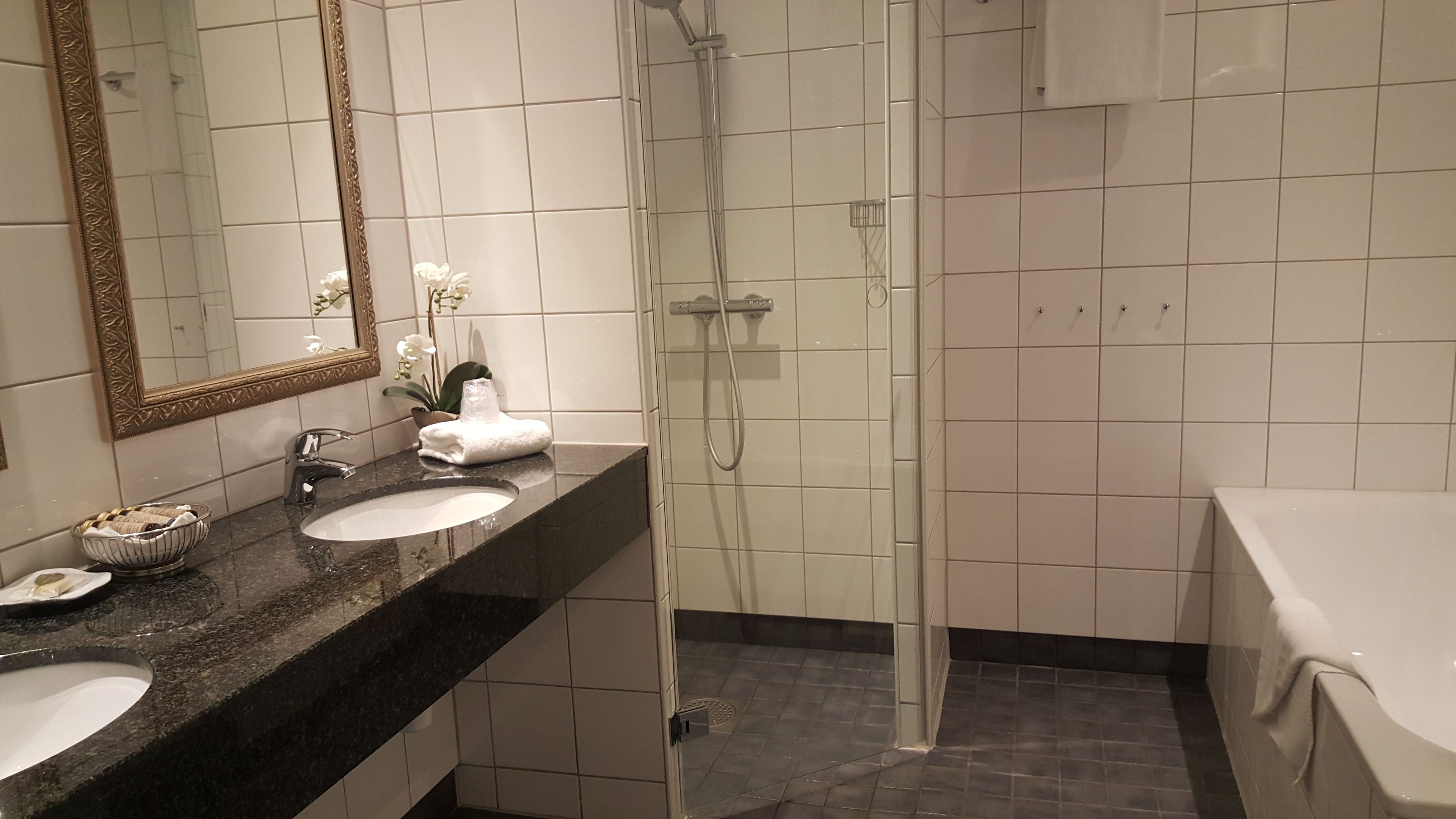 Ein Badezimmer mit Waschbecken, Spiegel, Dusche und Badewanne.