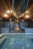 Una piscina interior moderna con techo de madera y paredes de azulejos.