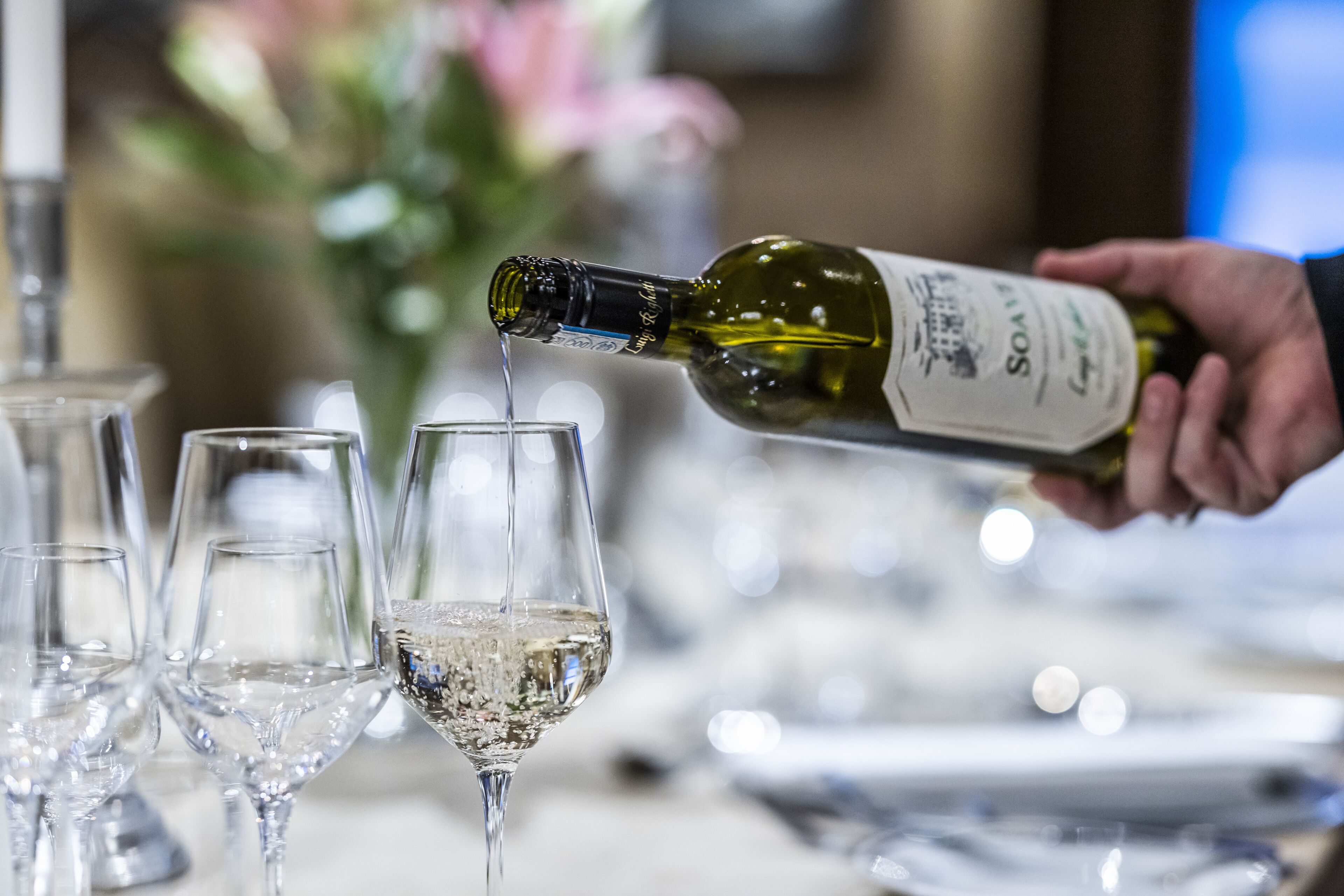 A hand pouring a bottle of wine into a glass.