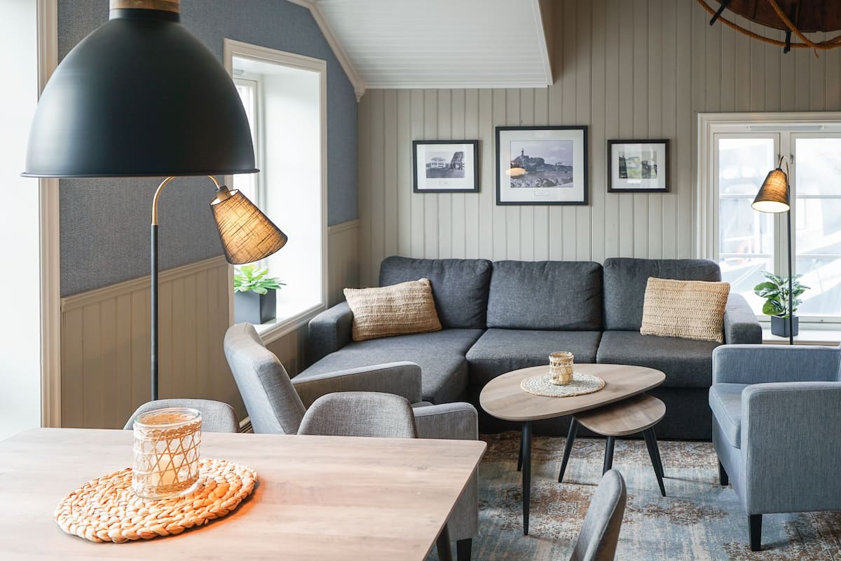 A modern living room with a grey sofa, a round coffee table, and a wooden dining table with a placemat.