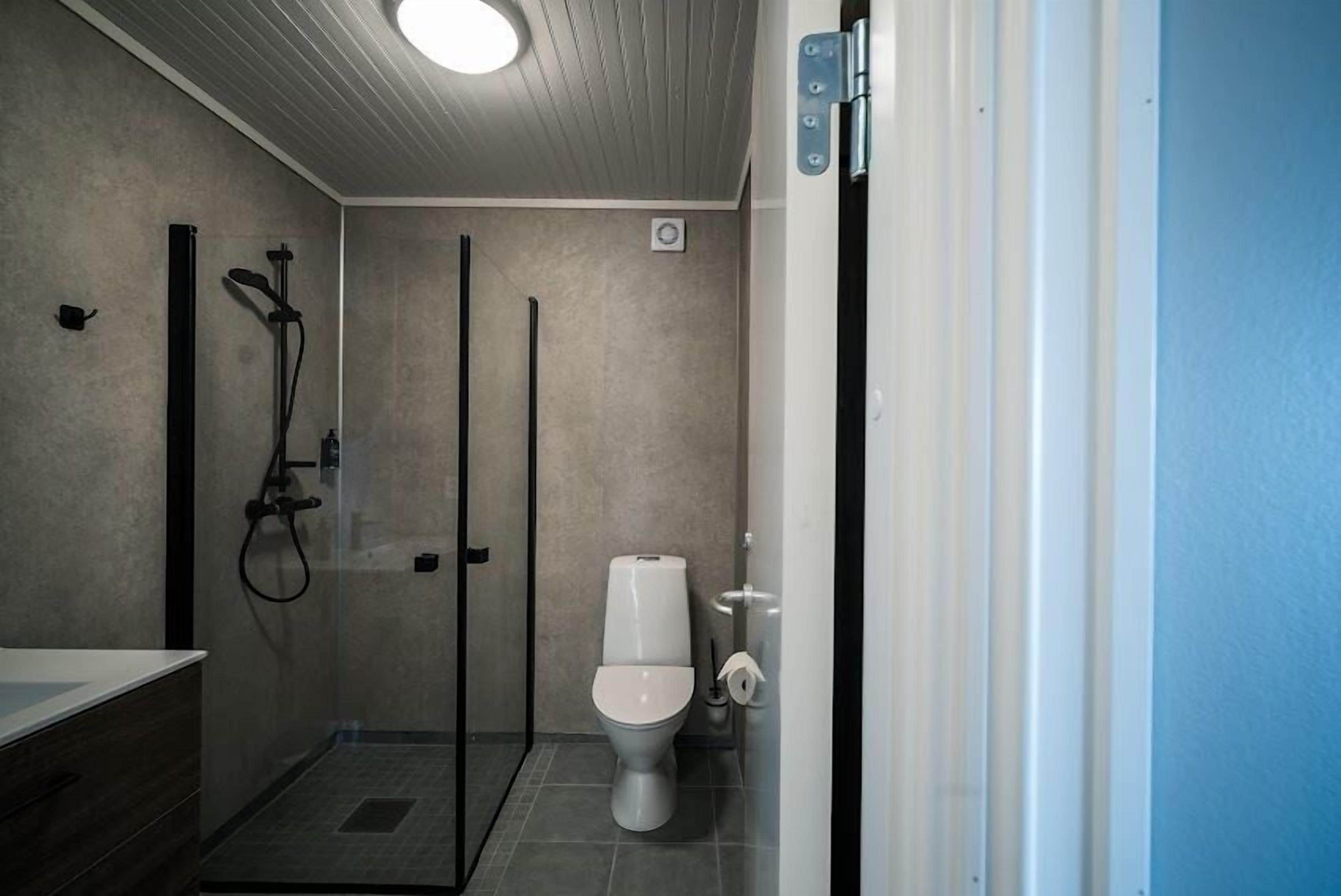 A modern bathroom with a glass-enclosed shower, a toilet, and a sink with a wooden vanity.