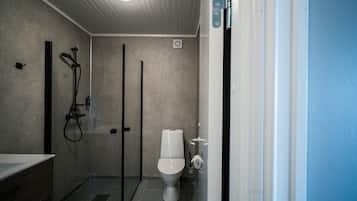 A modern bathroom with a glass-enclosed shower, a toilet, and a sink with a wooden vanity.