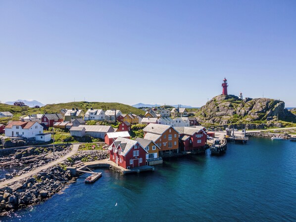Un pueblo costero con casas tradicionales de color rojo, un faro y un litoral rocoso.