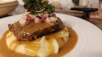 A plate of food with a meat dish, mashed potatoes, and a garnish.