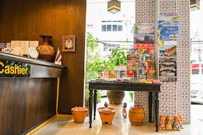 A reception desk with a 'Cashier' sign, a large vase, and a table with various items and a map.