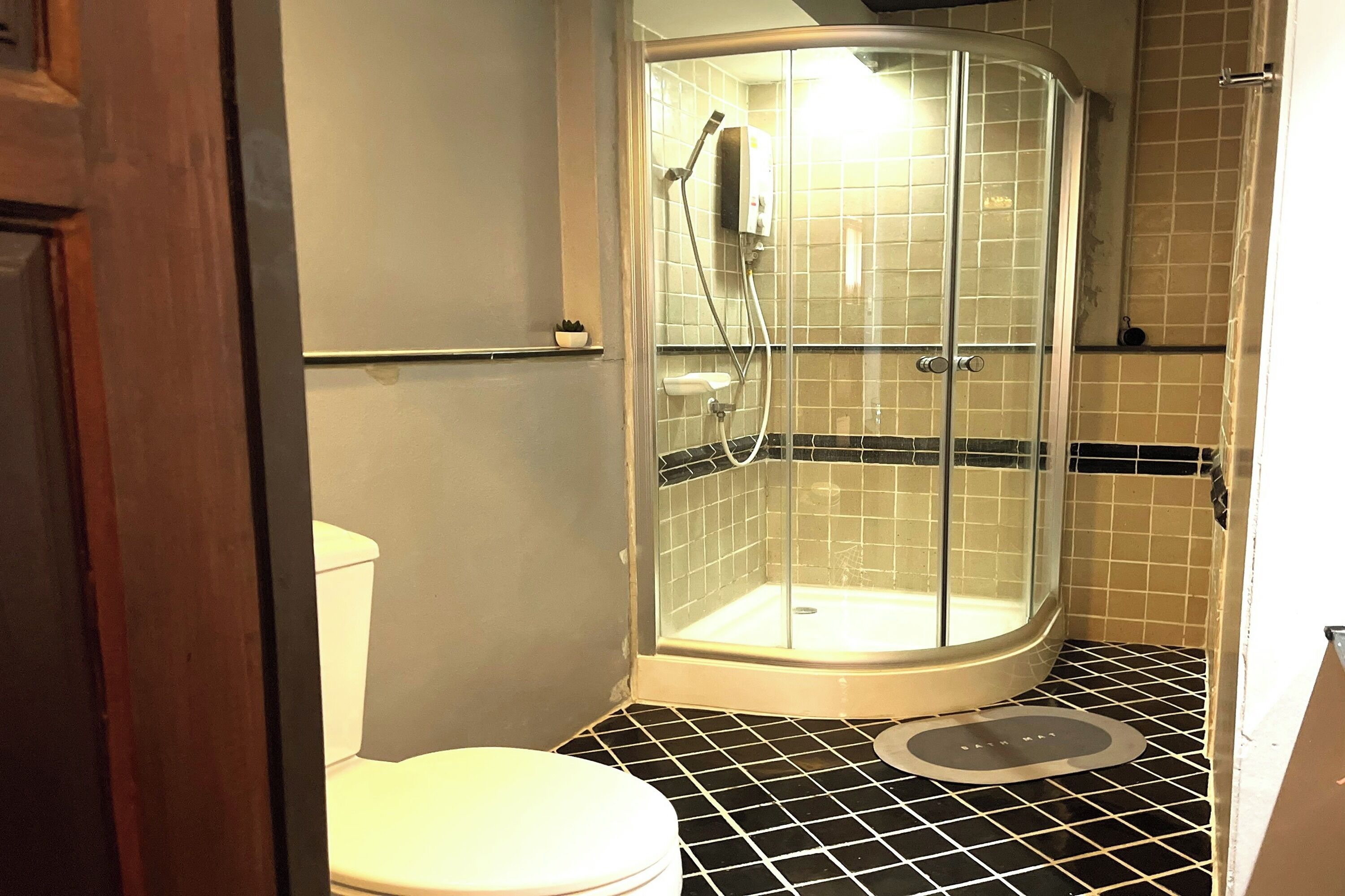 A bathroom with a glass-enclosed shower, a toilet, and a tiled floor.