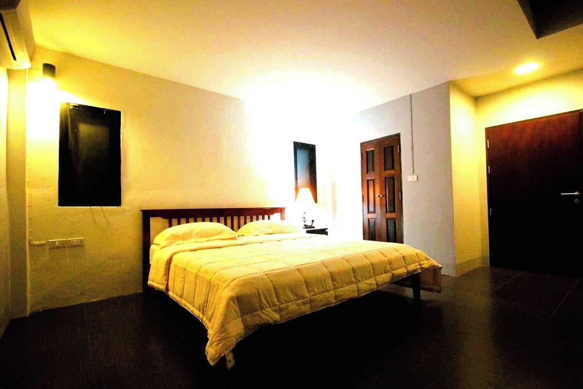 A room with a bed, a nightstand, and a wall-mounted light fixture.