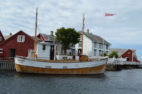 A boat named "HILDING" docked at a pier with a red building in the background.
