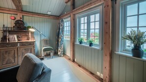 A cozy room with wooden beams, a fireplace, and large windows overlooking a scenic view. - Håholmen Havstuer - by Classic Norway Hotels (Averoy)