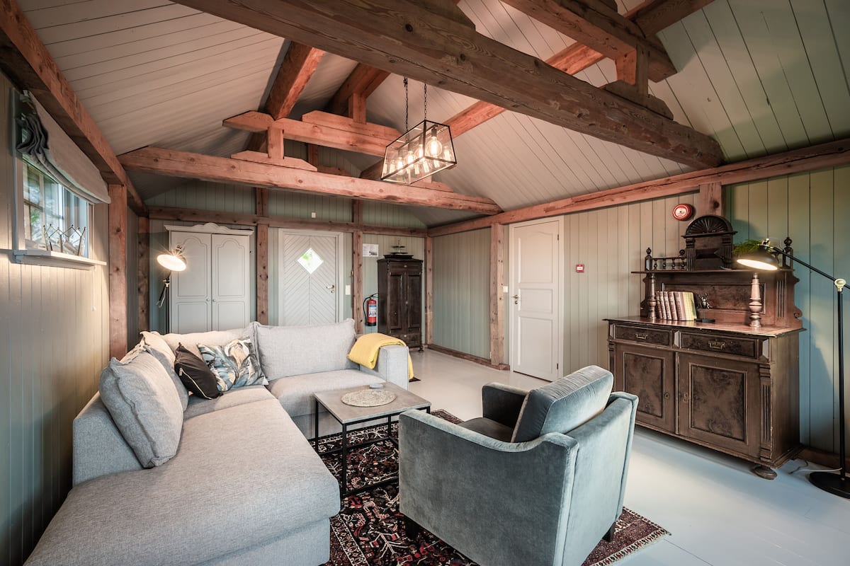 Una sala de estar acogedora con un sofá, un sillón y un aparador de madera.