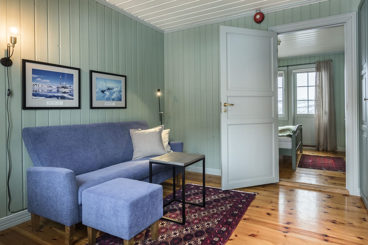 Una habitación con un sofá azul, una mesita y dos cuadros en la pared.
