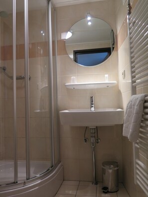 A bathroom with a glass-enclosed shower, a sink with a mirror above it, and a towel rack.