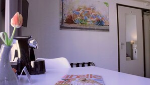 A dining table with a magazine, a vase with a tulip, and a coffee machine. - Stadshotel Rijssen (Rijssen)