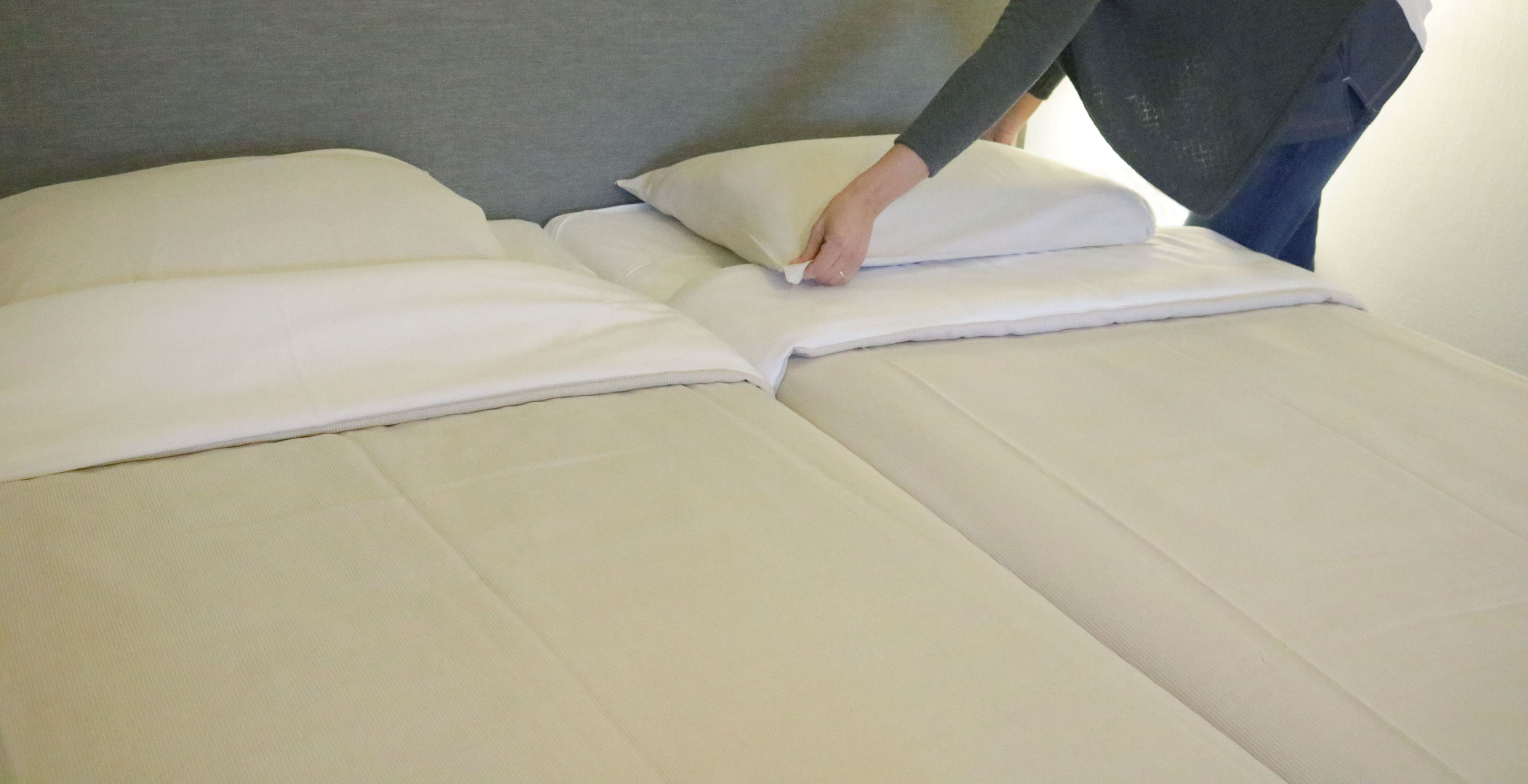 Una cama bien hecha con sábanas y almohadas blancas.