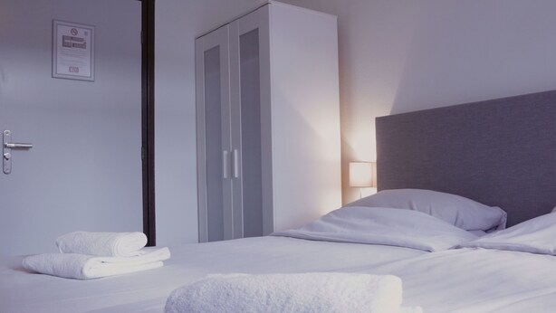 A hotel room with a bed, a wardrobe, and a door with a sign. - Stadshotel Rijssen (Rijssen)