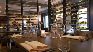 A restaurant with a long table set for dining, wine bottles on shelves, and a candle on the table. - Stadshotel Rijssen (Rijssen)