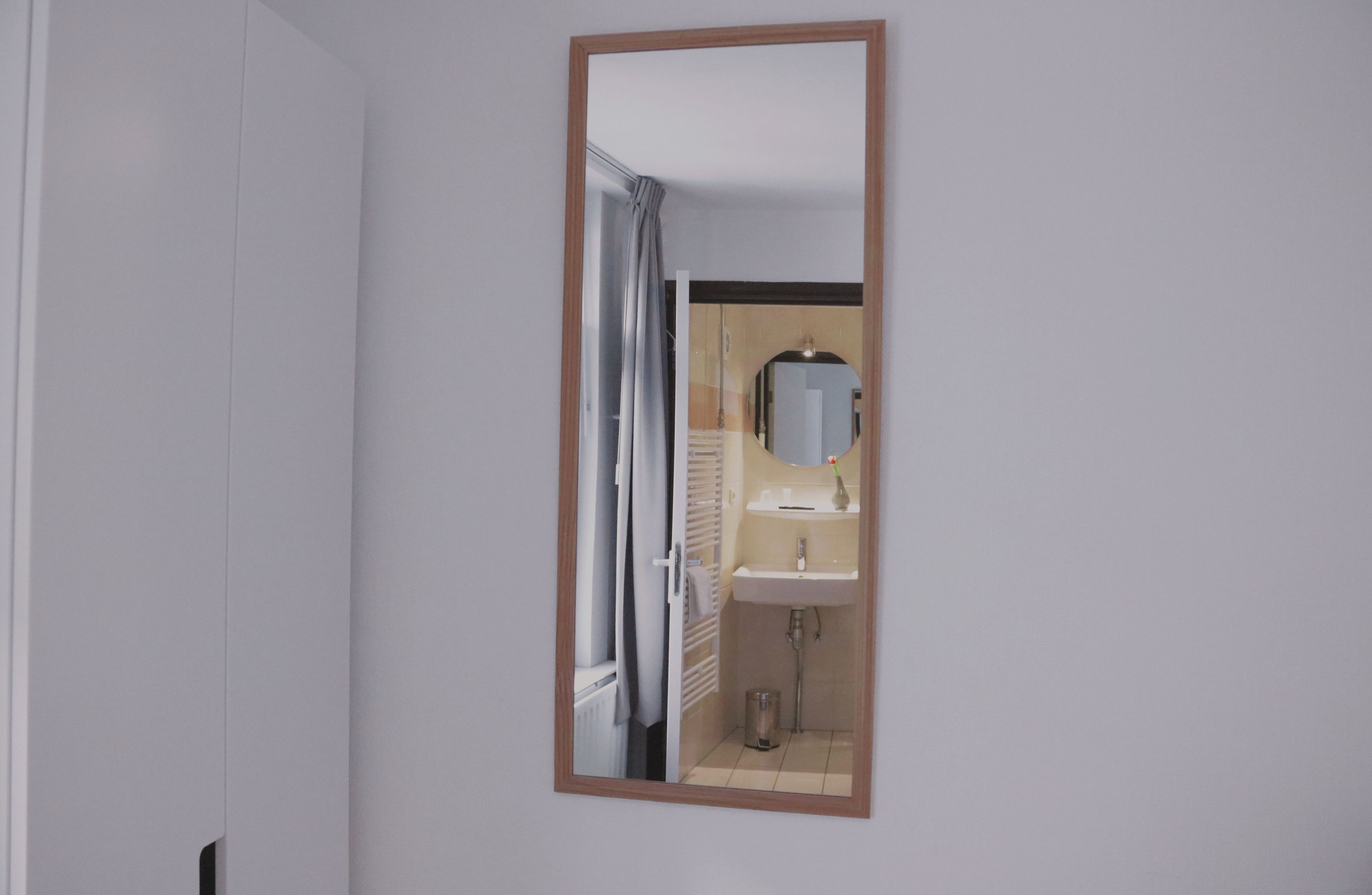 A bathroom with a mirror, sink, and towel rack.