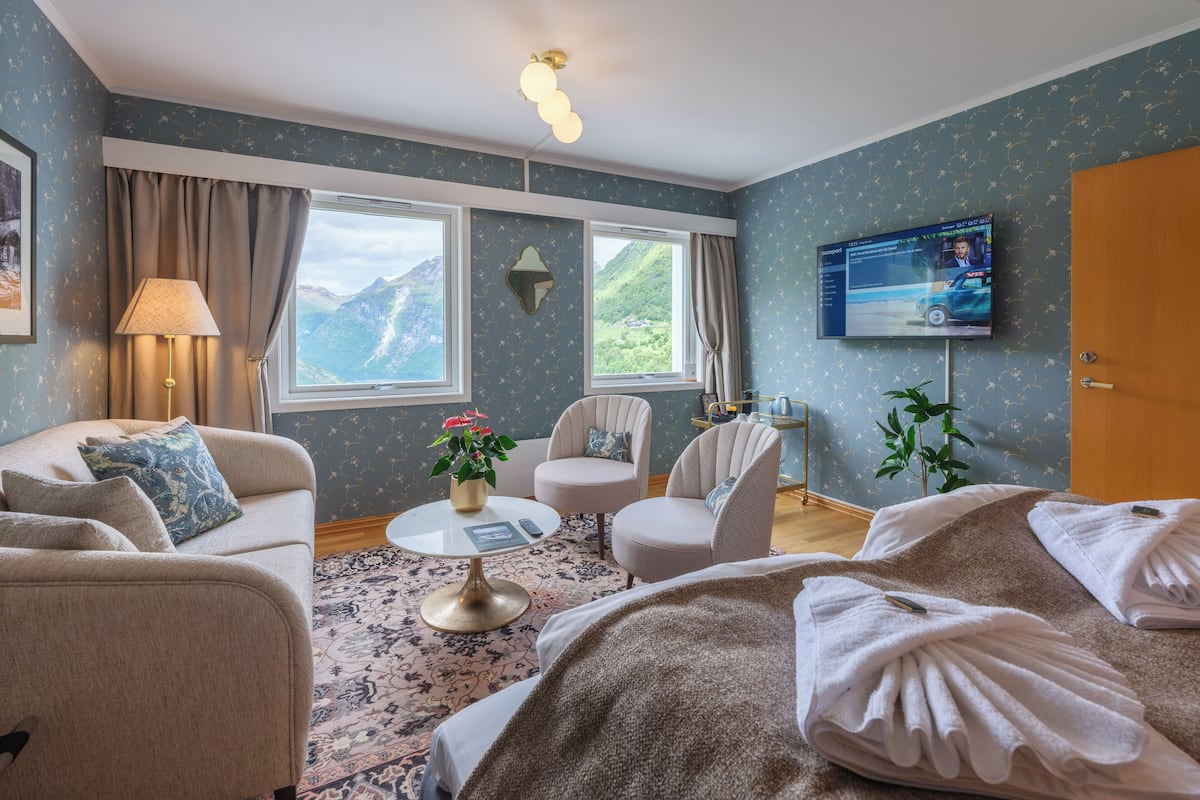 A cozy living room with a sofa, armchairs, a coffee table, and a TV.