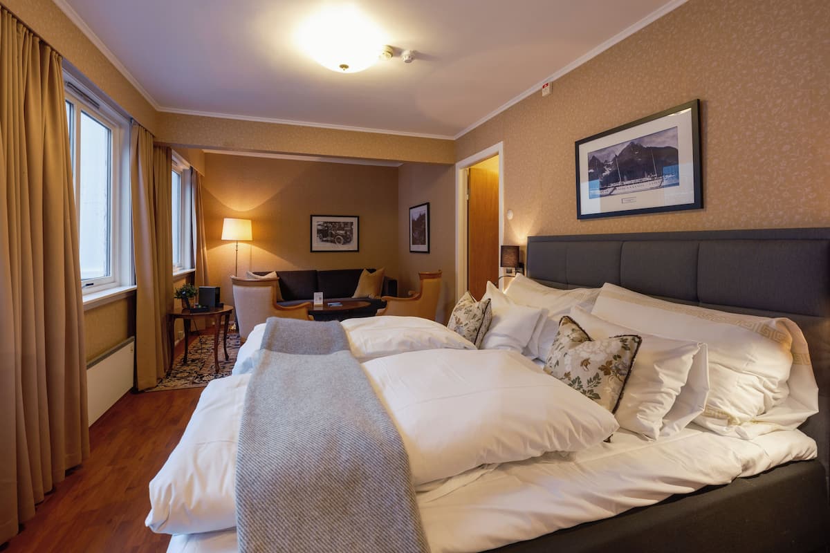 A hotel room with a large bed, a desk, a chair, and a lamp.