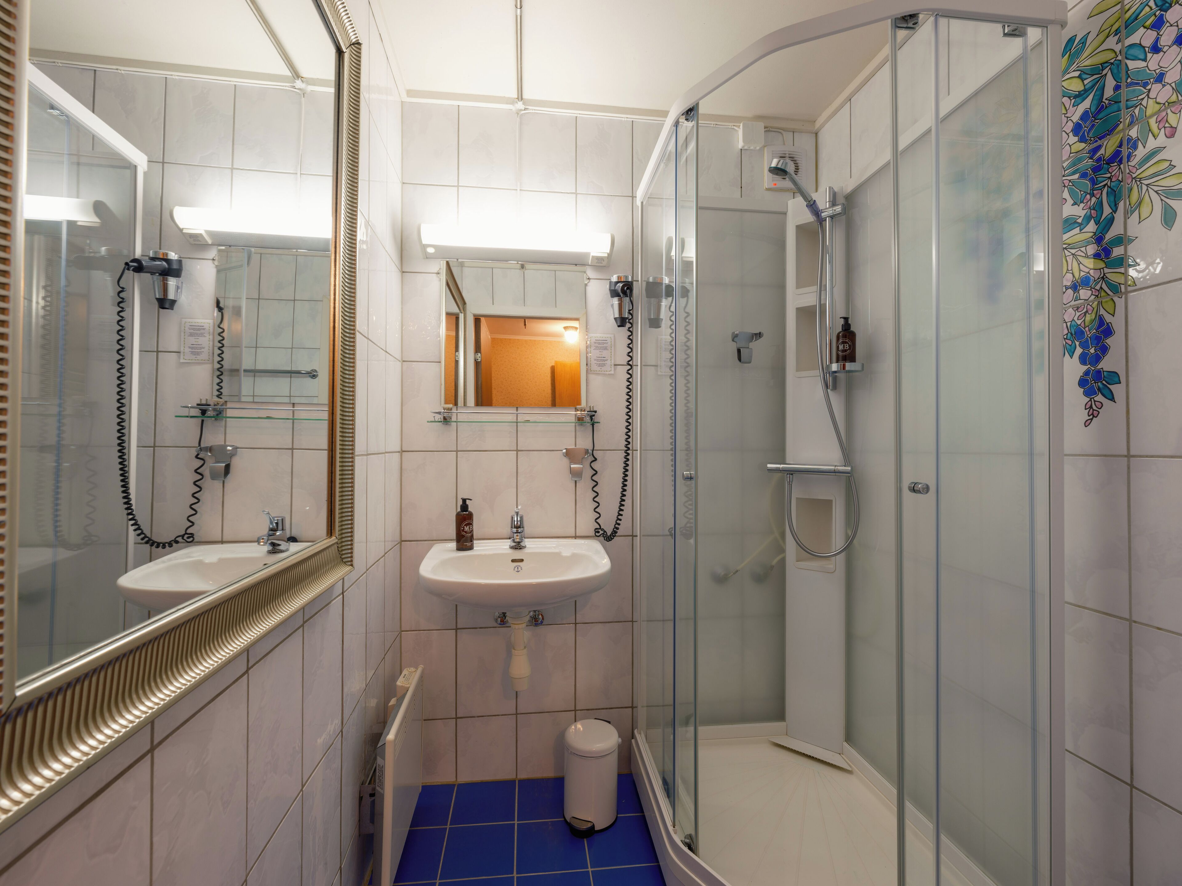 A modern bathroom with a glass shower enclosure, a sink with a mirror, and a toilet.