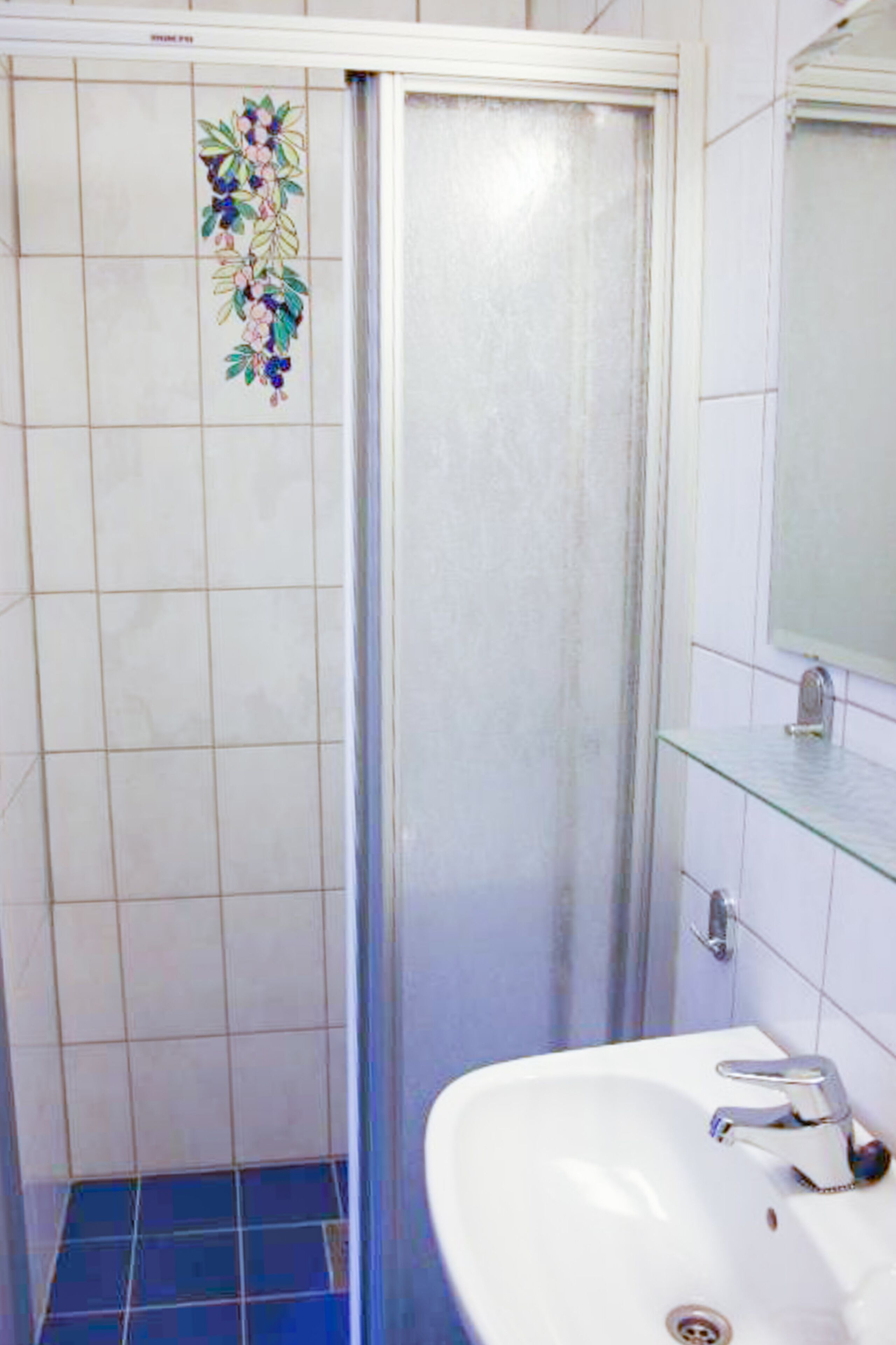 A bathroom with a shower, a sink, and a mirror.