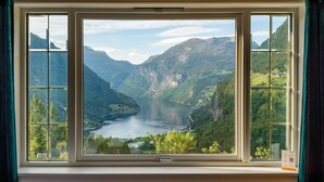A window with a view of a lake surrounded by mountains.