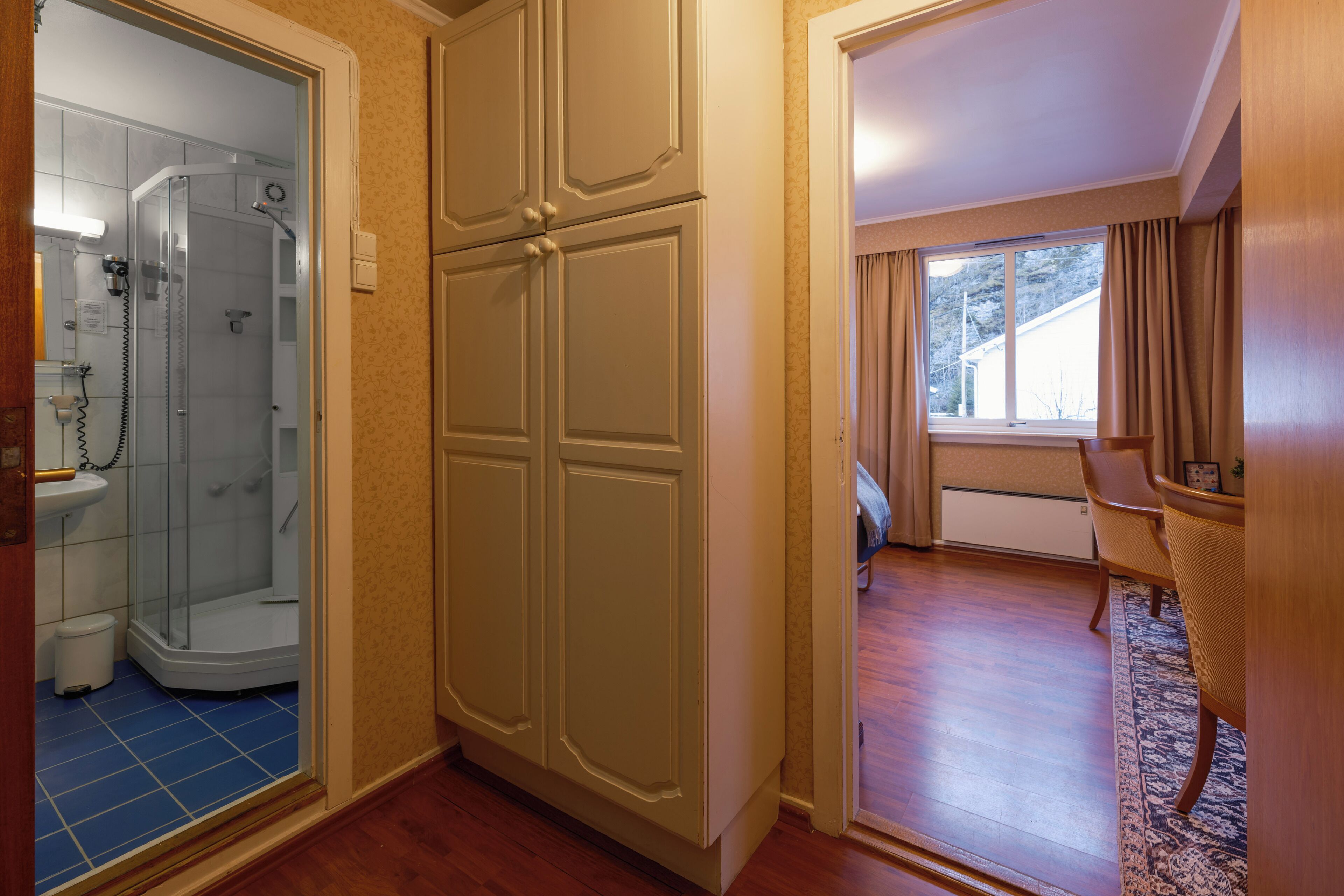 A room with a walk-in closet, a shower area, and a dining area with a view of the outdoors.