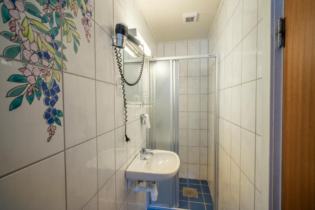 Un baño con lavamanos, secador de pelo y cabina de ducha.