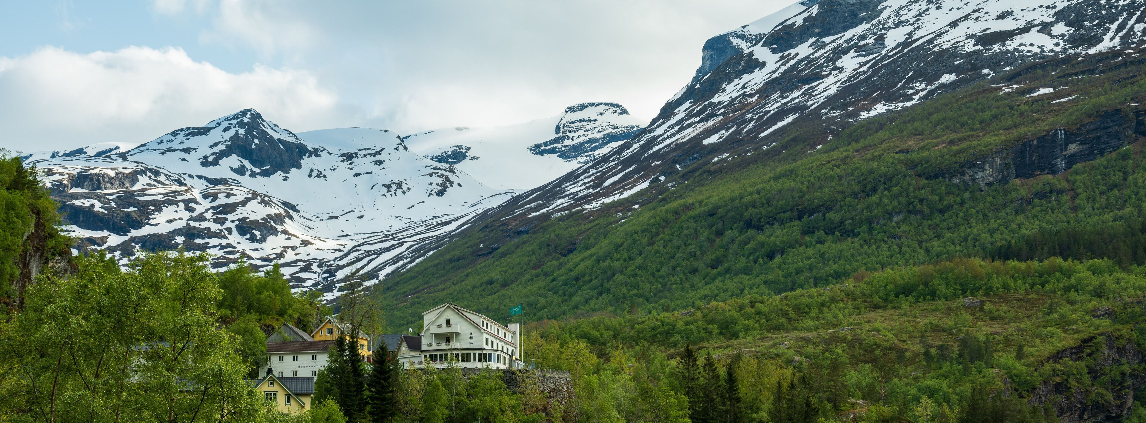 A mountain lodge with a view of snow-capped peaks and lush greenery.