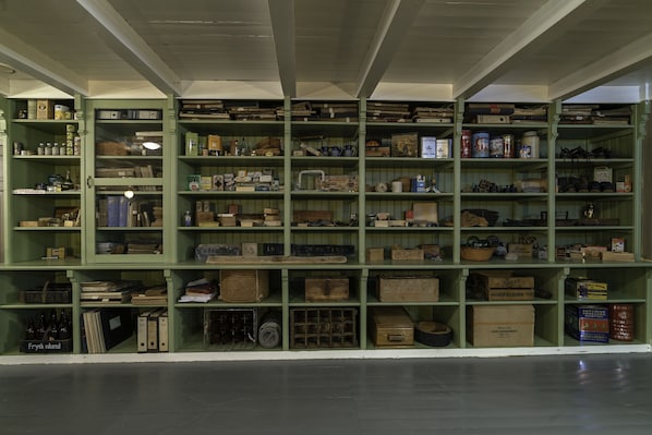 Un espacio amplio y abierto con estanterías verdes llenas de diversos objetos, como cajas, botellas y recipientes.