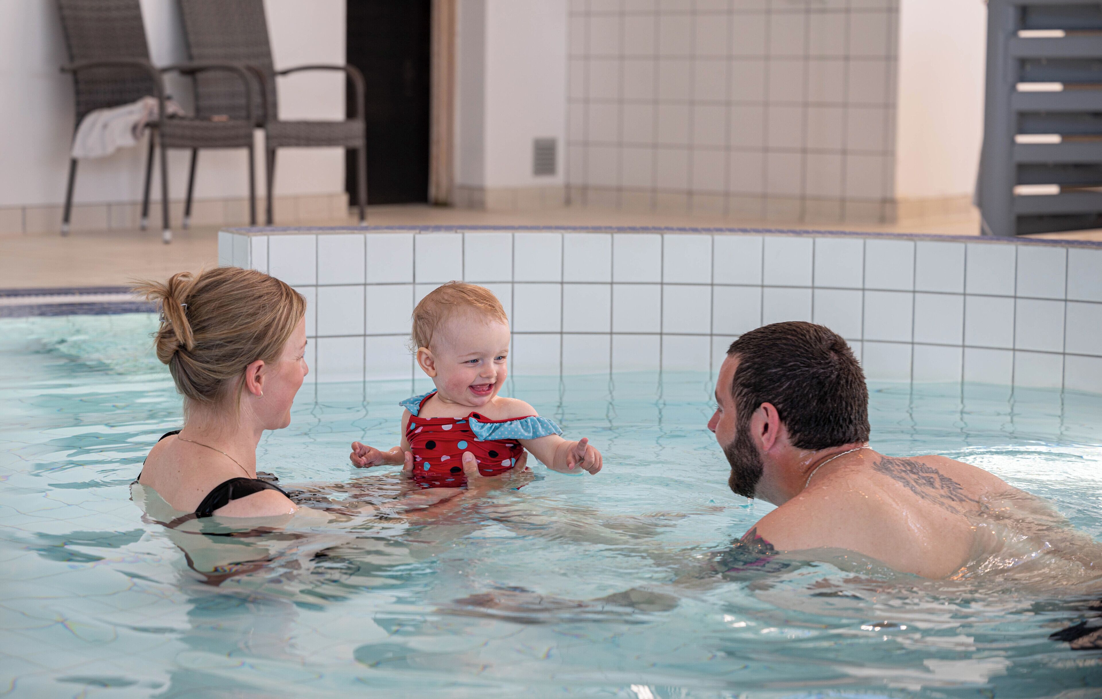 Una piscina con pareti e pavimento piastrellati, e lettini da relax.
