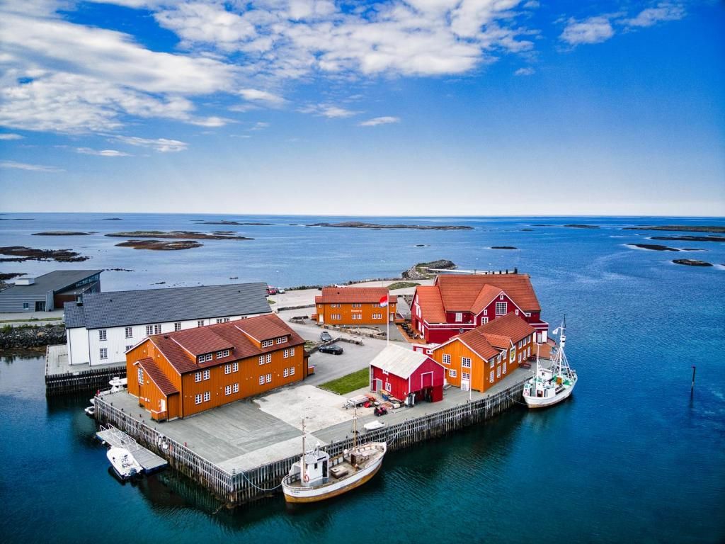 Complejo de edificios costeros con varias construcciones, un muelle y un bote.
