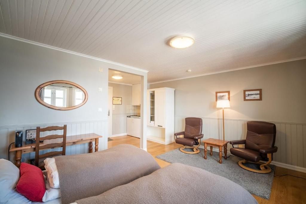 A room with a bed, a desk, two chairs, a mirror, and a lamp.