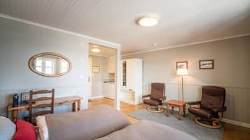 Una habitación con cama, escritorio, dos sillas, espejo y lámpara.