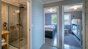 Un baño moderno con cabina de ducha de vidrio, tocador de madera y un perchero visible.