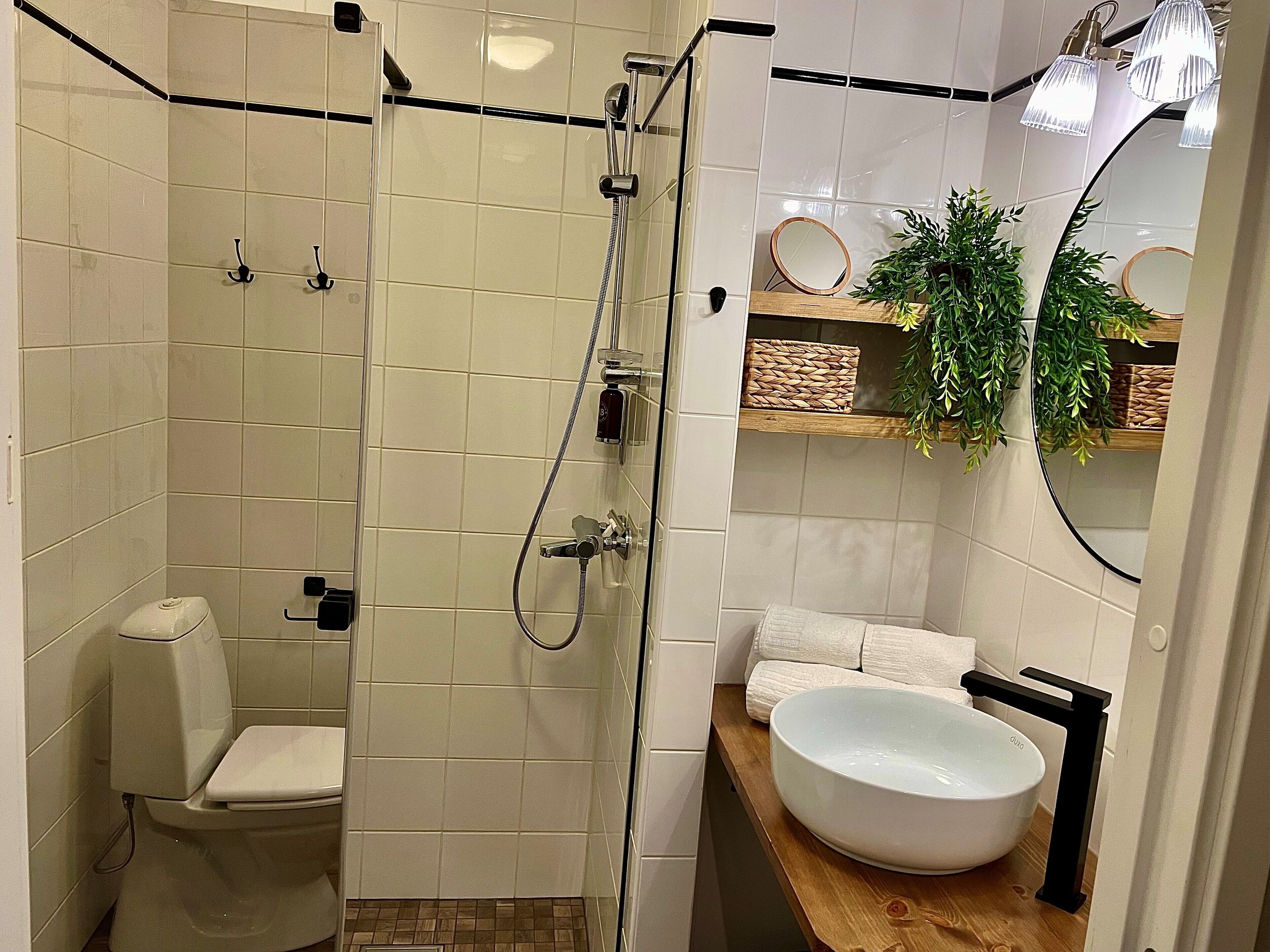 Een moderne badkamer met een inloopdouche, toilet en een groot wastafel.