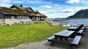 Un edificio frente al mar con césped y mesas de picnic.