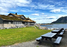 A coastal building with a grassy lawn and picnic tables.