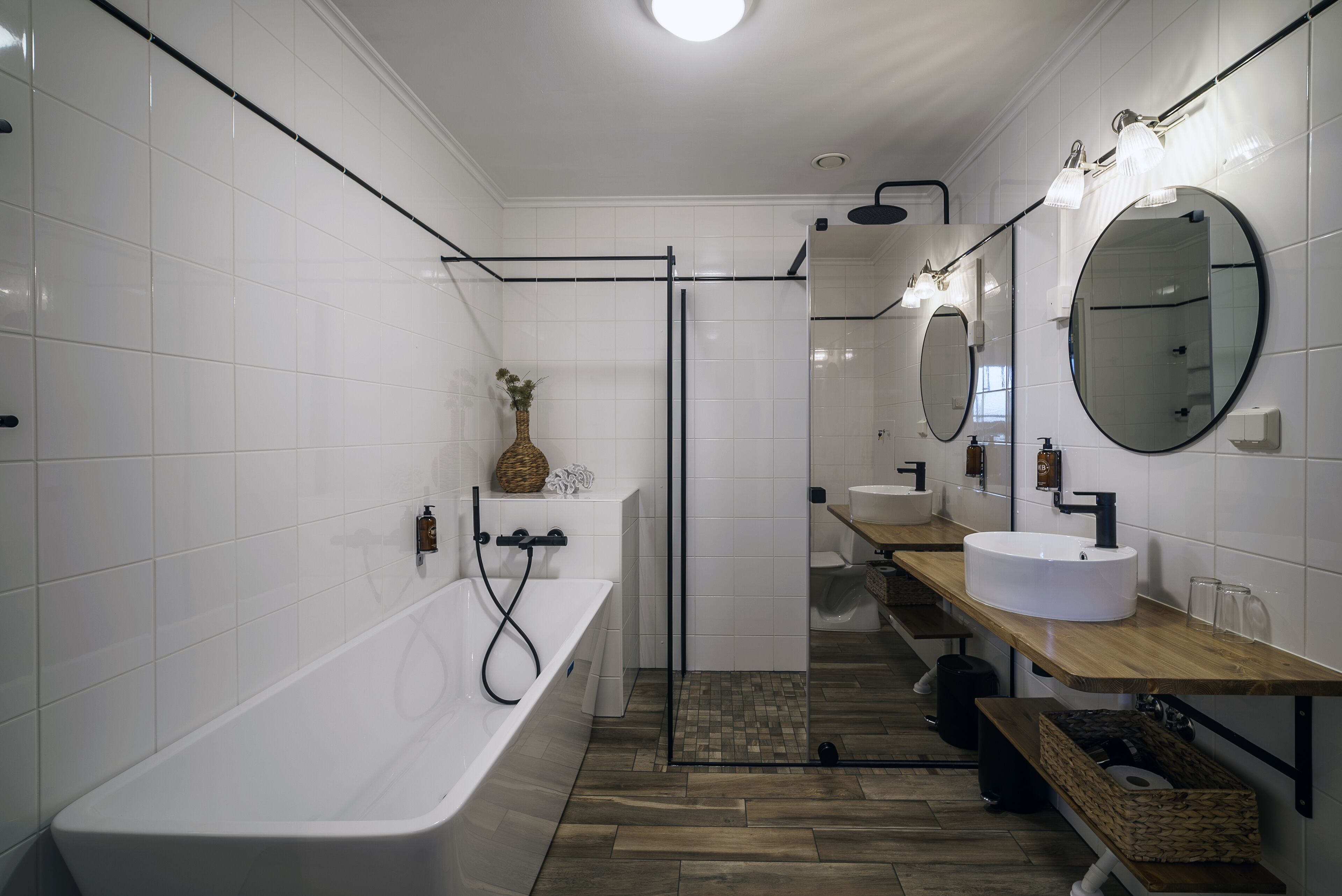A modern bathroom with a freestanding bathtub, a glass-enclosed shower, and two sinks with mirrors.