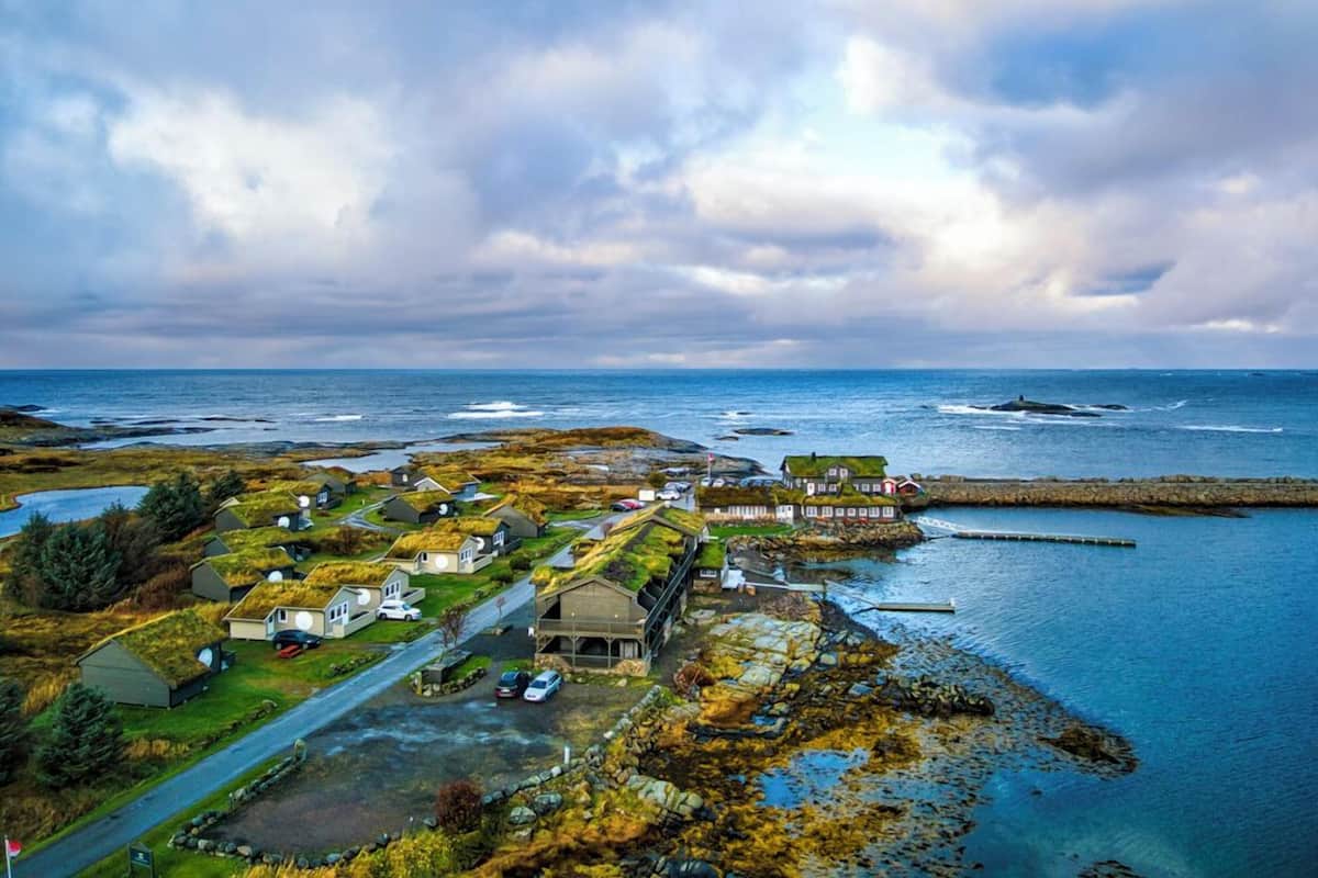 A coastal village with houses featuring green roofs, a stone pier, and a view of the sea.