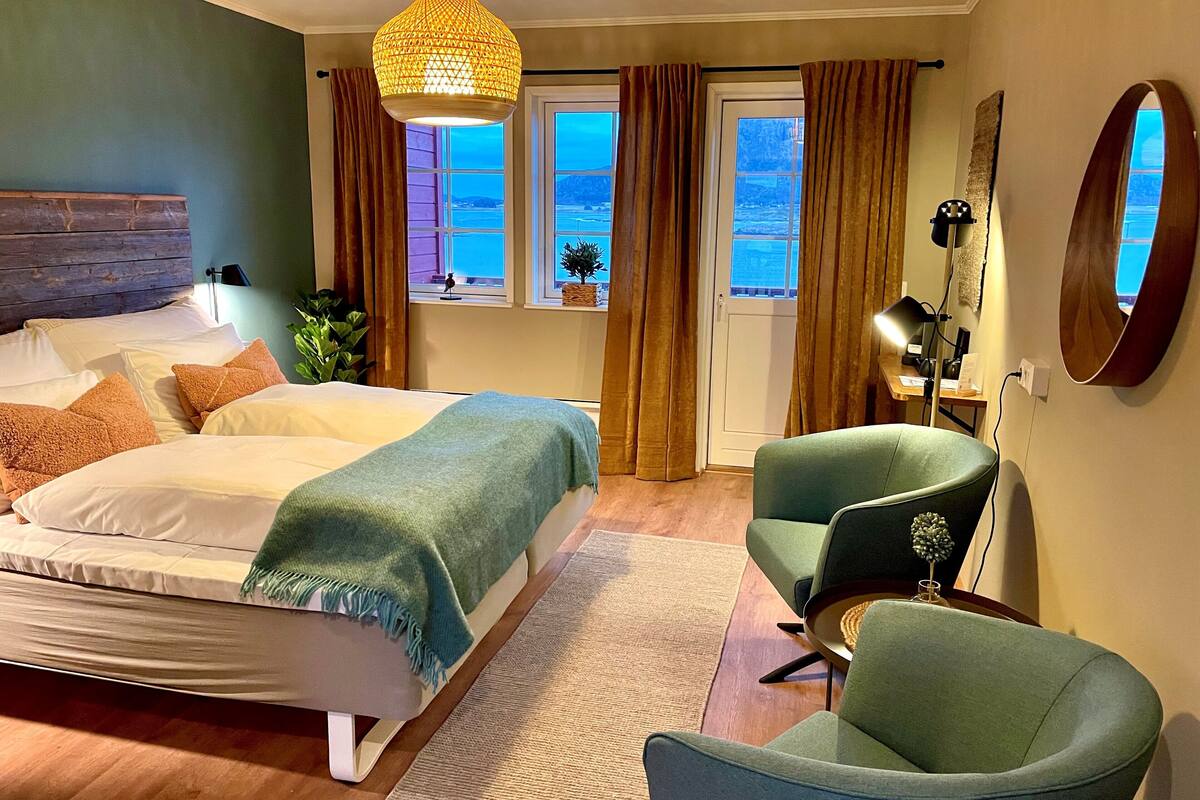 A bedroom with a bed, a chair, a desk, and a window with curtains.