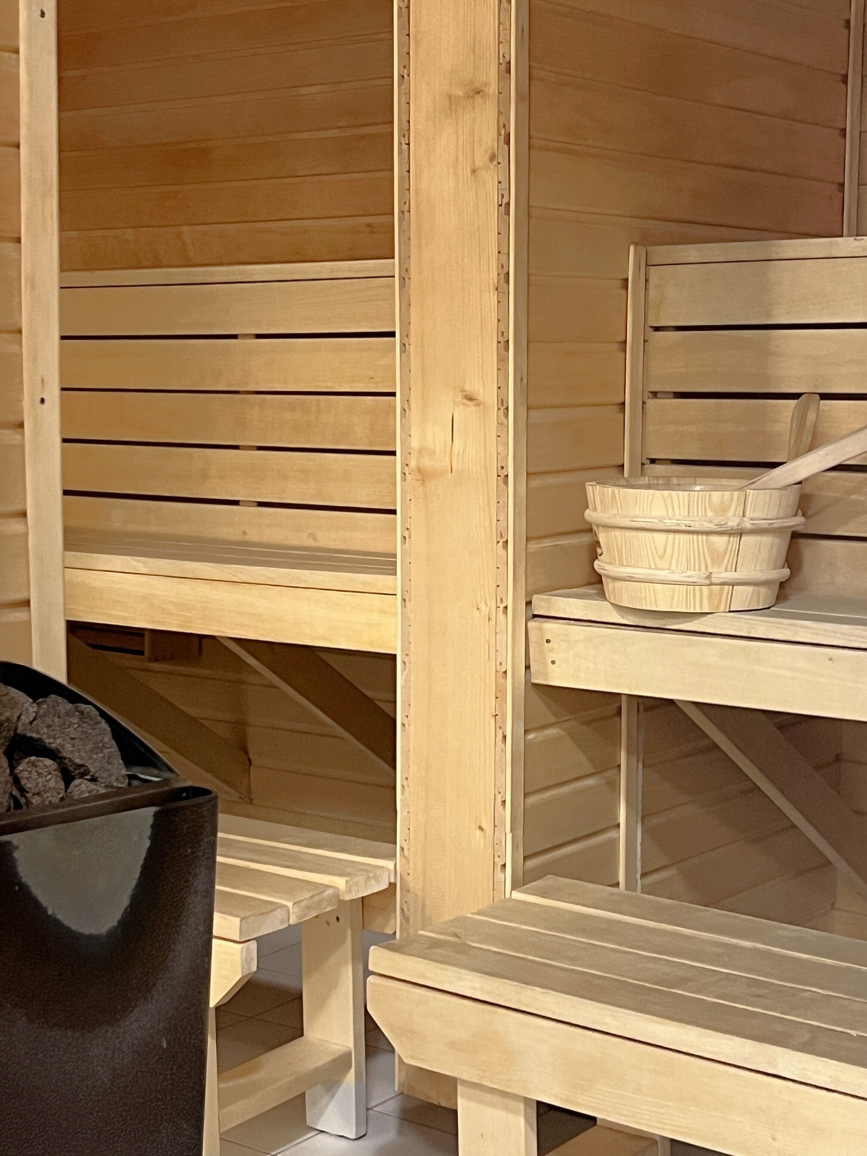 Een houten sauna met banken en een houten tafel met een kom en een houten lepel.