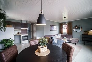 Una sala de estar moderna con una mesa de comedor, sofás y una zona de cocina.