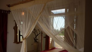 A room with a bed, a window, and a decorative plant. - Kamili View Apartment in Zanzibar (Kiwengwa)