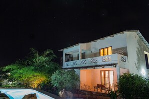 A two-story house with a balcony, a swimming pool, and a patio area with outdoor furniture. - Kamili View Apartment in Zanzibar (Kiwengwa)