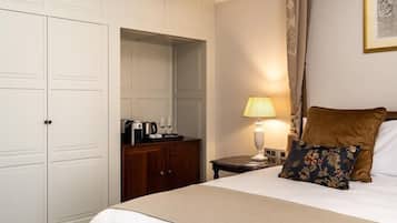 A hotel room with a bed, a nightstand, a lamp, a wooden dresser, and a wardrobe.