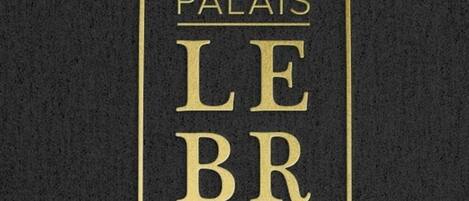 Un letrero con el texto 'PALAISES LE BRUN' en una tipografía serif, enmarcado por una decoración.