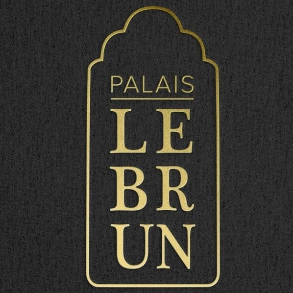 Un letrero con el texto 'PALAISES LE BRUN' en una tipografía serif, enmarcado por una decoración.