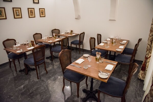 Un comedor con varias mesas dispuestas para el servicio, cada una con sillas y vajilla.